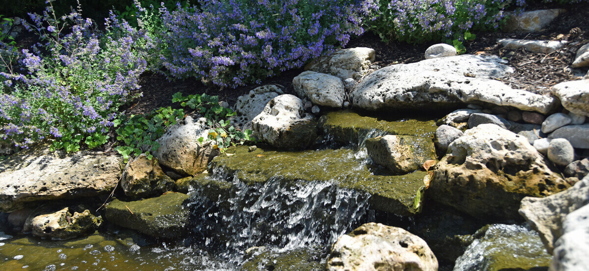 Outdoor living area with rocks and waterfall, completed by Embassy Landscape Group.