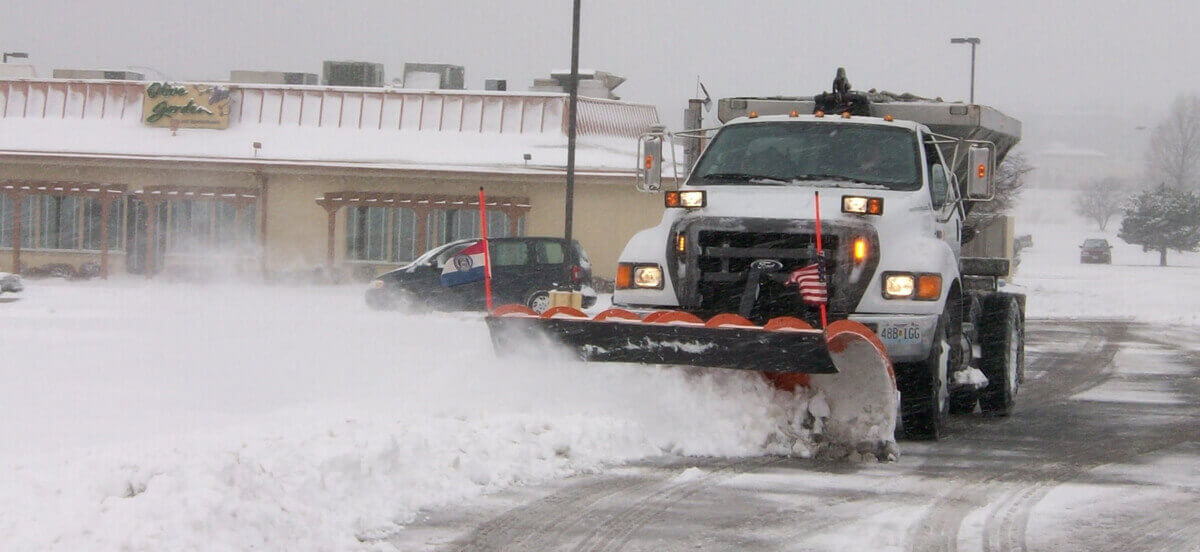 Truck plows snow to remove from roads.